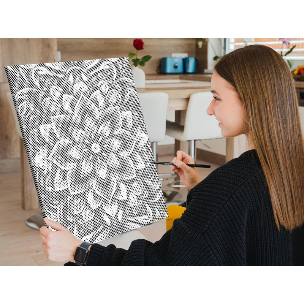 Kvinna som håller en svartvit mönstrad målning i en avslappnad inomhusmiljö